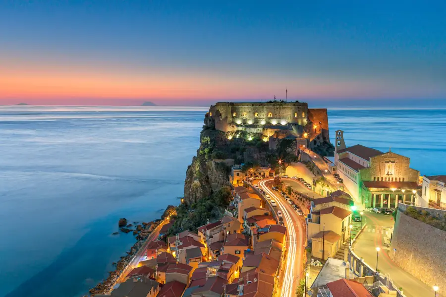 Castello Ruffo e Chiesa di San Rocco con luci della città e mare al tramonto