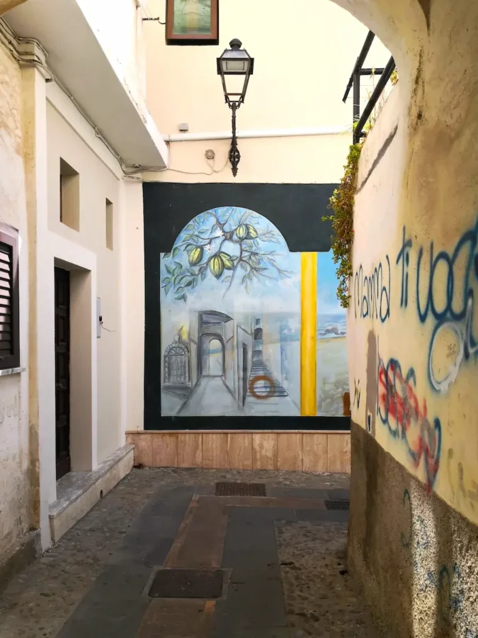 Vicolo caratteristico del centro storico di Diamante con un murales raffigurante frutti di cedro sul fondo