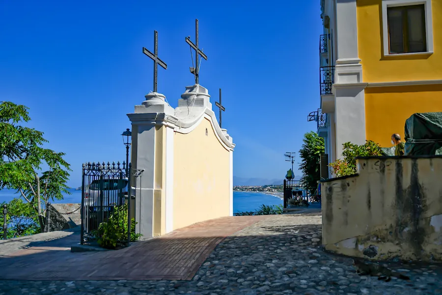 Scorcio del centro storico di Diamante con edicola votiva a tre croci e vista sul mare Tirreno